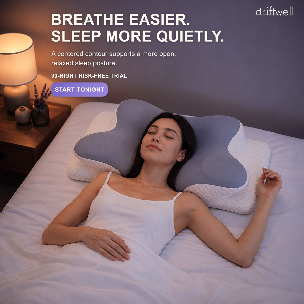 A woman asleep on her back on the Driftwell Contour Pillow in a warmly lit bedroom, the centred contour supporting an open, relaxed sleep posture